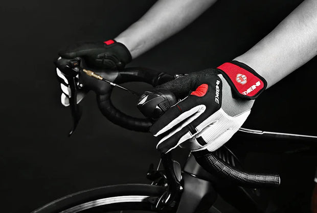 Person wearing black and white cycling gloves with red accents on a bike.