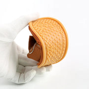 Orange textured cup with brown base held by a white glove on a white background