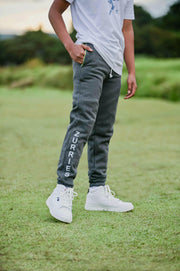 Person wearing gray sweatpants with 'Zurries' branding on a grassy field.