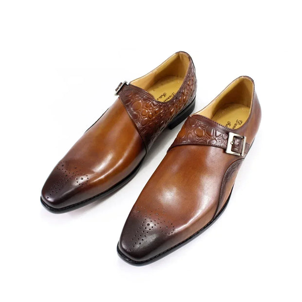 Pair of brown leather dress shoes with embossed design on a white background