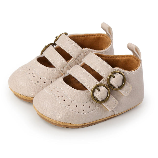 Pair of beige baby shoes with brown soles on a white background