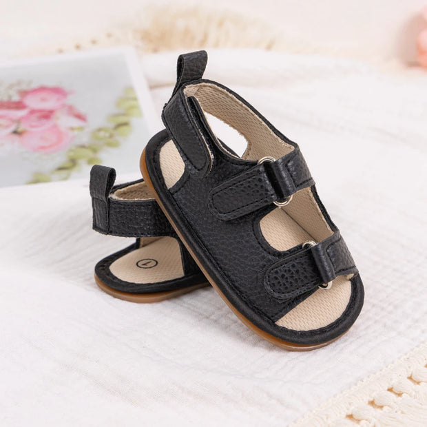 Black baby sandals with velcro straps on a light background