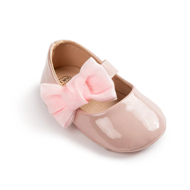 Pink baby shoe with a bow on a white background