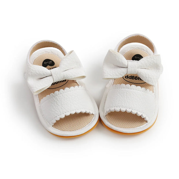White baby sandals with bow details on a white background