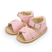 Pair of pink baby sandals with beige soles on a white background