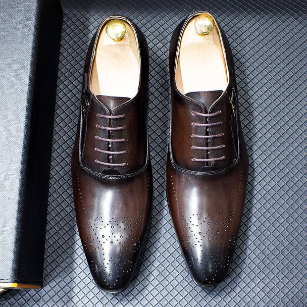 Pair of brown dress shoes with gold accents on a textured gray surface