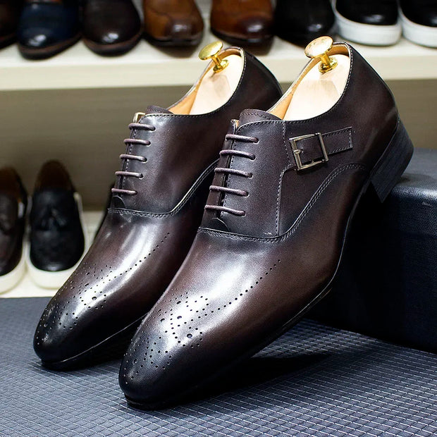 Pair of brown leather dress shoes with a buckle on a textured surface.
