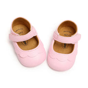 Pair of pink baby shoes with a white background