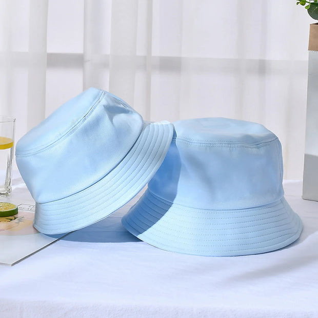 Two light blue bucket hats on a white surface with a blurred background