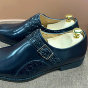 Pair of navy blue shoes with gold buckles on a textured surface