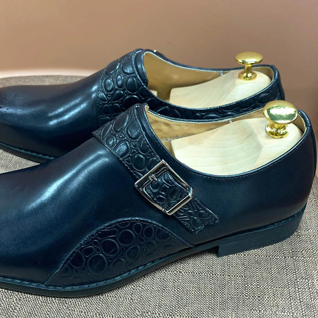Pair of navy blue shoes with gold buckles on a textured surface