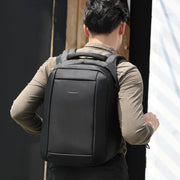 Person wearing a black backpack with a neutral background