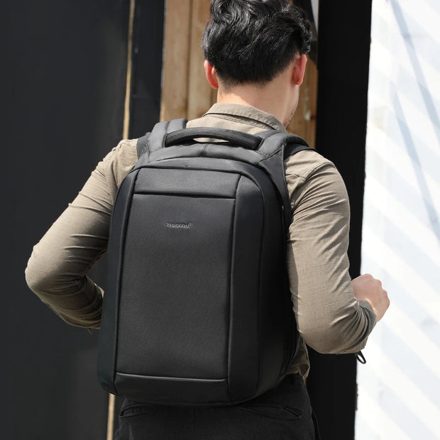 Person wearing a black backpack with a neutral background