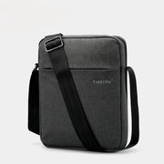 Gray shoulder bag with black strap on a light gray background