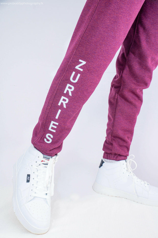 Maroon sweatpants with 'Zurries' branding worn with white sneakers on a light gray background