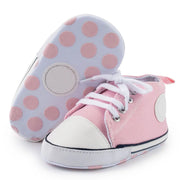 Pink high-top sneakers with white soles and pink polka dots on a white background