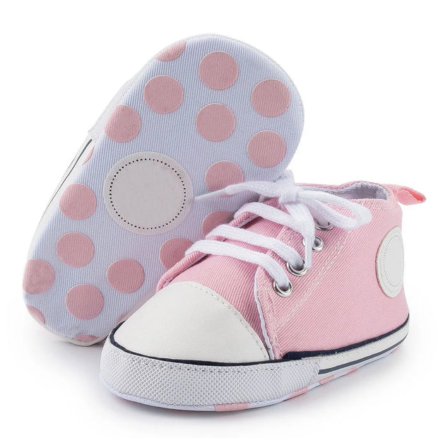 Pink high-top sneakers with white soles and pink polka dots on a white background