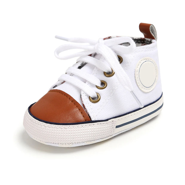 White baby shoe with brown accents on a white background