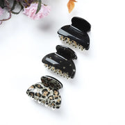 Set of black and gold hair clips on a white background with floral decorations.