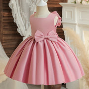 Pink dress with a large bow on a mannequin against a blurred indoor background