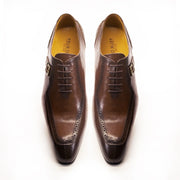 Pair of brown dress shoes with black soles on a white background