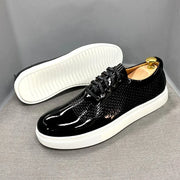 Black shiny shoes with white soles on a gray background