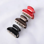 Three hair clips in red, black, and bronze on a white background