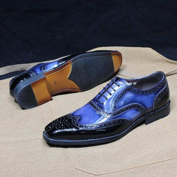 Blue dress shoes with brown soles on a beige surface