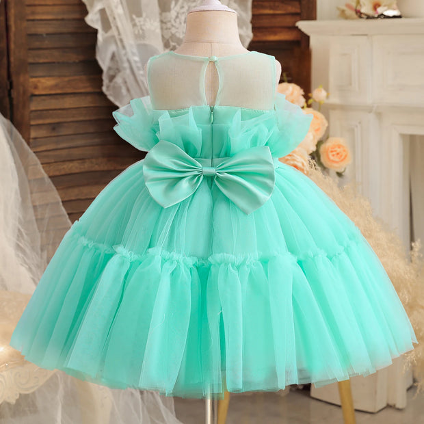 Mint green dress with a large bow on a mannequin against a decorative background.