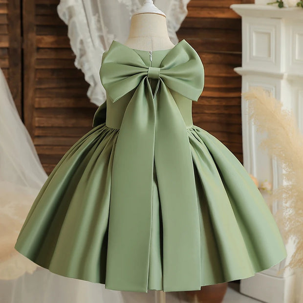 Green dress with a large bow on a mannequin against a decorative background