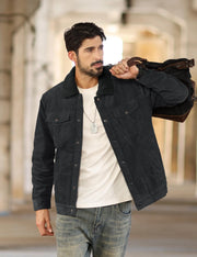 Man wearing a black jacket holding a brown leather bag in an urban setting