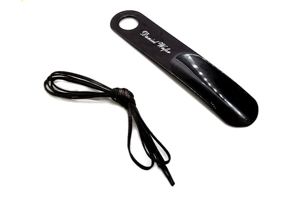 Black shoehorn with a cord on a white background