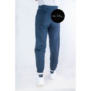 Blue sweatpants worn by a person on a white background with a brand logo.