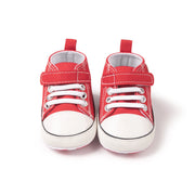 Red baby shoes with white soles on a white background