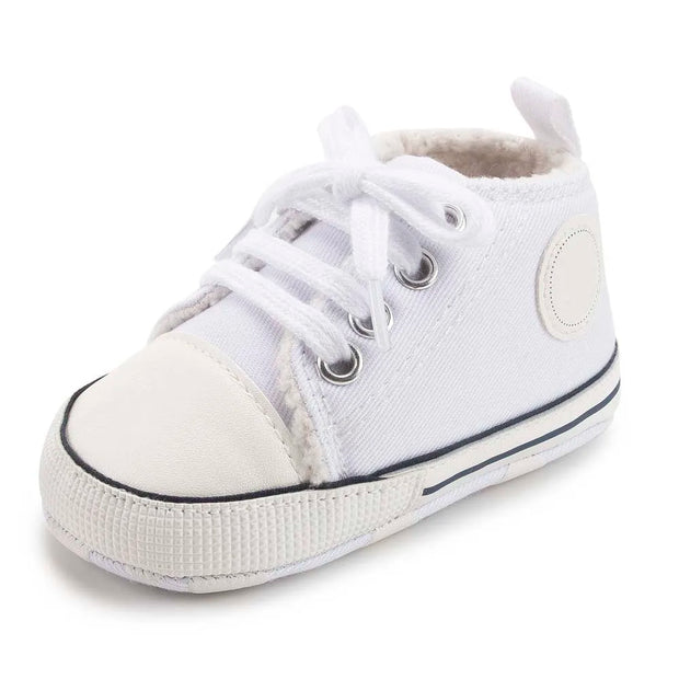 White baby shoe with black sole on a white background