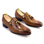 Pair of brown leather loafers with tassels on a white background