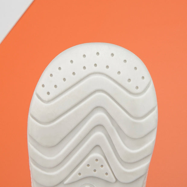 Close-up of a white shoe sole with wavy pattern on an orange background