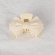 Cream-colored bow-shaped object on a light gray background