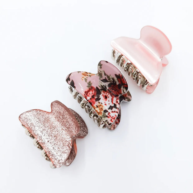 Three decorative hair clips with floral and glitter designs on a white background