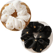 White and black scrunchies with gold star patterns on a white and brown background