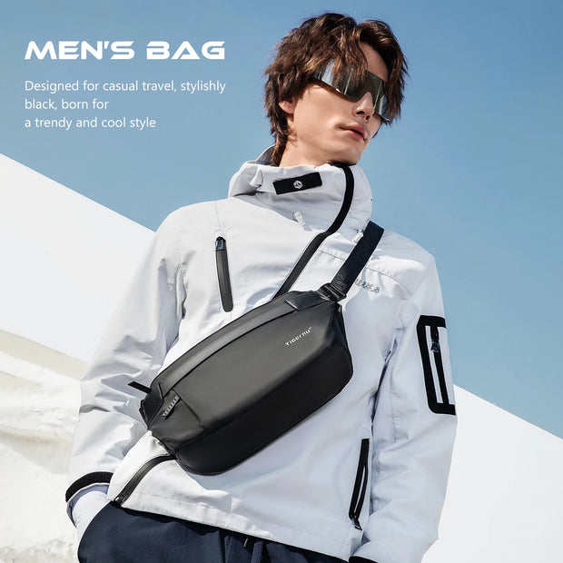 Man wearing a black crossbody bag with a clear blue sky background