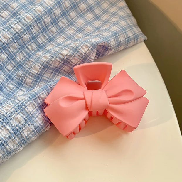 Pink bow-shaped object on a checkered fabric background