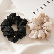 Black and beige scrunchies with star patterns on a white surface