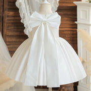 White dress with a large bow on a mannequin against a wooden background