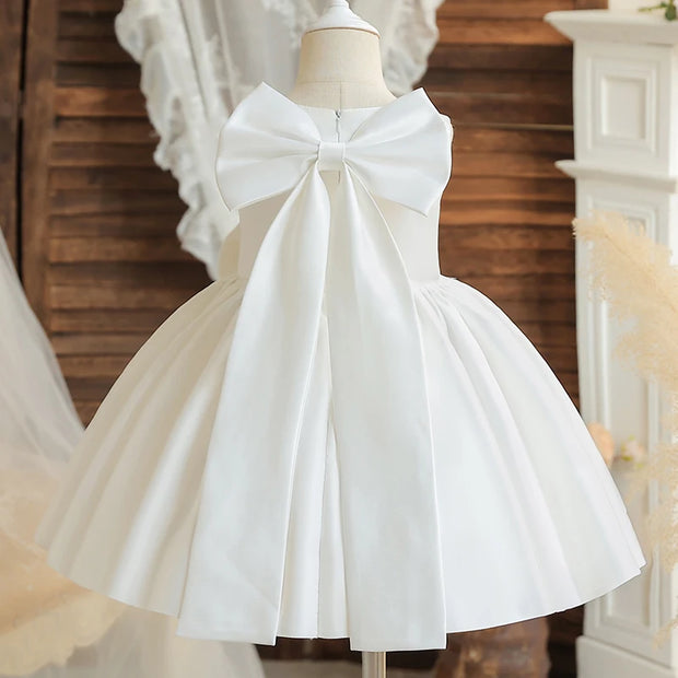 White dress with a large bow on a mannequin against a wooden background