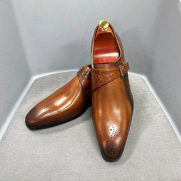 Pair of brown leather shoes with a buckle on a gray surface