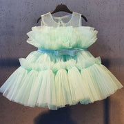 Light green tulle dress with a bow on a hanger against a neutral background