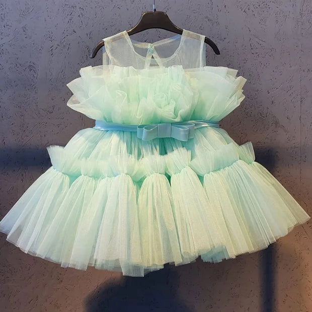 Light green tulle dress with a bow on a hanger against a neutral background