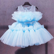 Light blue tulle dress on a hanger against a textured purple wall.