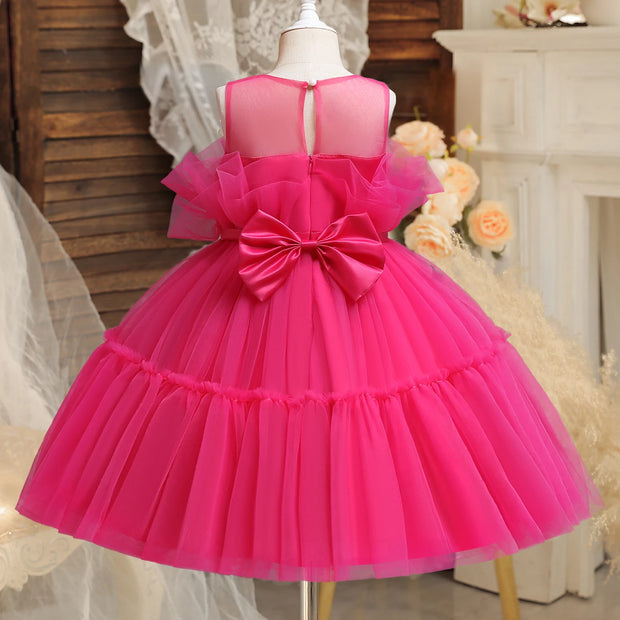 Pink dress with a large bow on a mannequin against a decorative background.